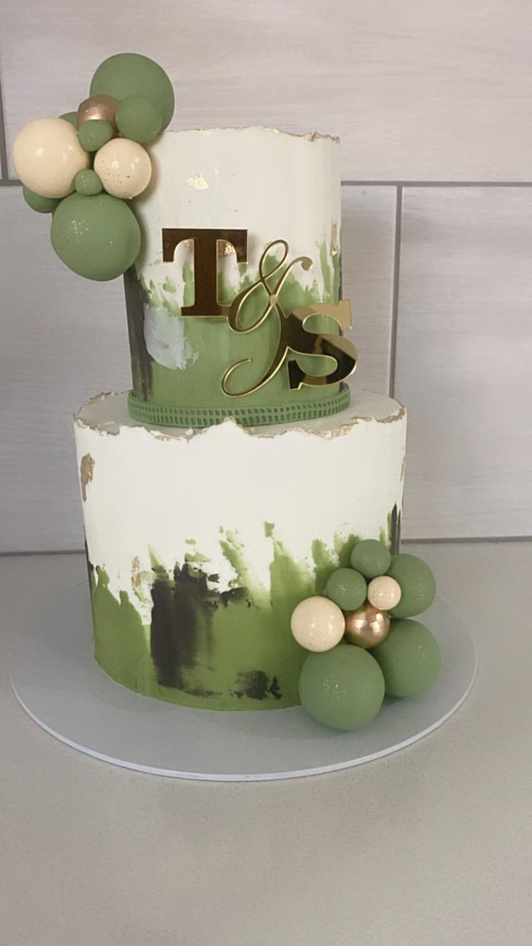 Two-tier olive green and white wedding cake with balloons